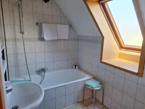 a bathroom with a tub and a sink and a window at Hof Junkernberg in Bispingen