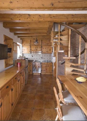 a large kitchen with wooden cabinets and a wooden table at Dolomiti Bellunesi in Belluno