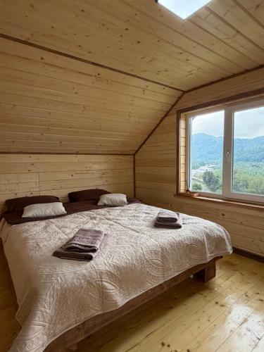 a bed in a wooden room with a large window at Садиба Смугар in Rostoki
