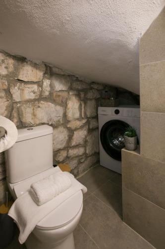 a bathroom with a toilet and a washer and dryer at Nine Muses Hospitality in Nea Irakleia