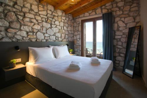 a bedroom with a large bed with a stone wall at Nine Muses Hospitality in Nea Irakleia