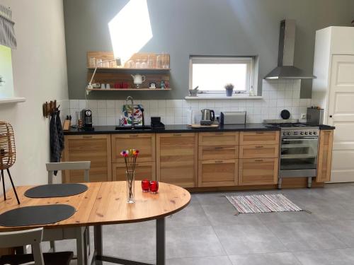 a kitchen with a wooden table and a table with flowers on it at UNIEK Bommelgaard, guesthouse in het prachtige Rivierenland! in Hurwenen
