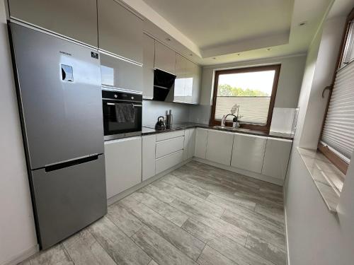 a kitchen with a stainless steel refrigerator and a window at Podlaska Oaza in Przejma Wielka