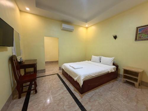 a bedroom with a bed and a desk and a television at Mohachey Guesthouse in Phumĭ Bavĕt (2)