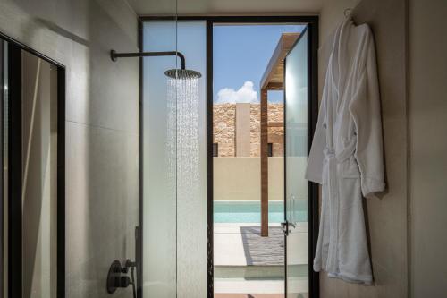 ein Badezimmer mit einer Glastür, die zu einem Pool führt in der Unterkunft Socrates Hotel & Villas Malia Beach in Malia