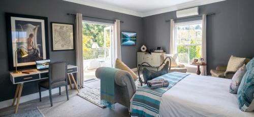 a bedroom with a bed and a desk and a window at Sandmartins in Suider-Paarl