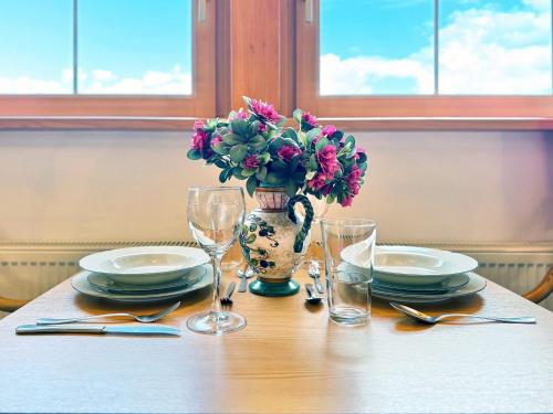 a table with plates and a vase with flowers in it at Sonnenhof Seeg 15 in Seeg