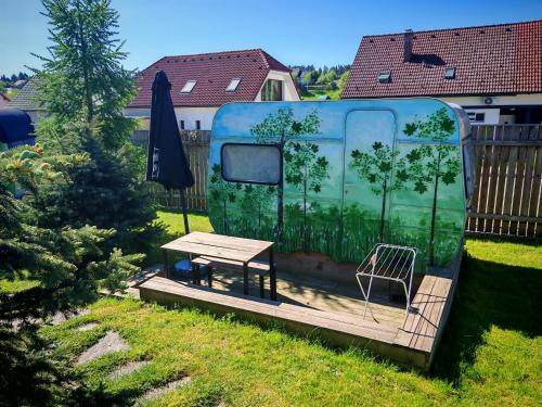 a caravan with a table and a bench in a yard at Glamping Langus in Topolšica
