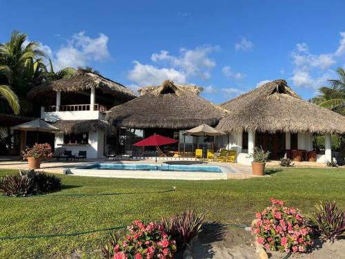a resort with a swimming pool and thatched roofs at Casa Fuente Ocean Villa in Santa María Colotepec