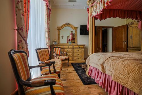 a bedroom with a bed and two chairs and a dresser at Zamek Dubiecko in Dubiecko