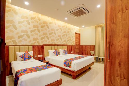 a hotel room with two beds and a table at FabHotel Golden Stay I in Bangalore