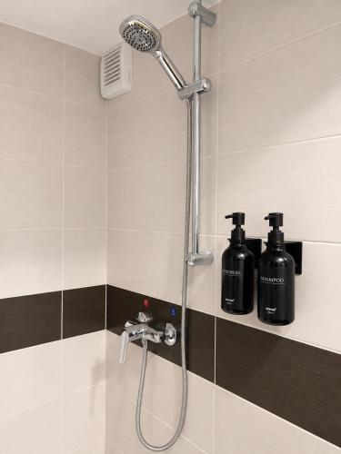 a shower in a bathroom with two black bottles at NEU! Fly & Stay Residence Frankfurt Airport Kelsterbach in Kelsterbach