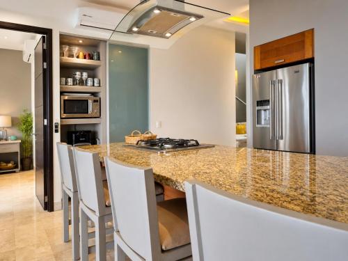 a kitchen with a granite counter top and white chairs at Bucerias, Beachfront Penthouse in Bucerías