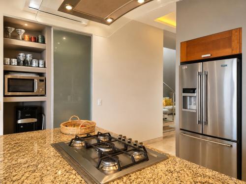 a kitchen with a stove and a stainless steel refrigerator at Bucerias, Beachfront Penthouse in Bucerías