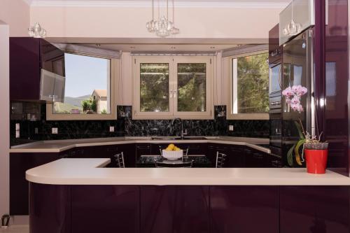 a kitchen with black cabinets and a sink and windows at Villa Guesto with Private Pool by MindYourVilla in Anafonítria