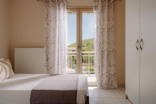 a bedroom with a bed and a large window at Villa Guesto with Private Pool by MindYourVilla in Anafonítria