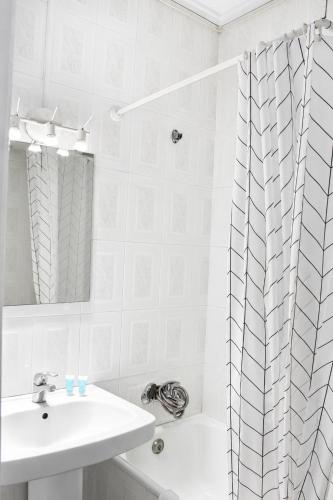 a white bathroom with a sink and a shower curtain at Malvarrosa Beach Rooms in Valencia