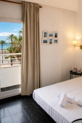 a bedroom with a bed and a window with a view at Malvarrosa Beach Rooms in Valencia