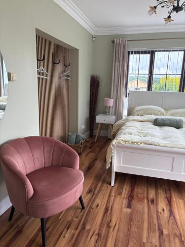 a bedroom with a white bed and a pink chair at Dreenan studio in Ballybofey