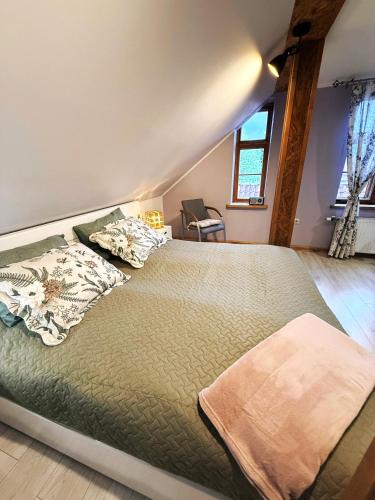 a bedroom with a bed with a green comforter at Rose & Vintage Mansard in Kuldīga