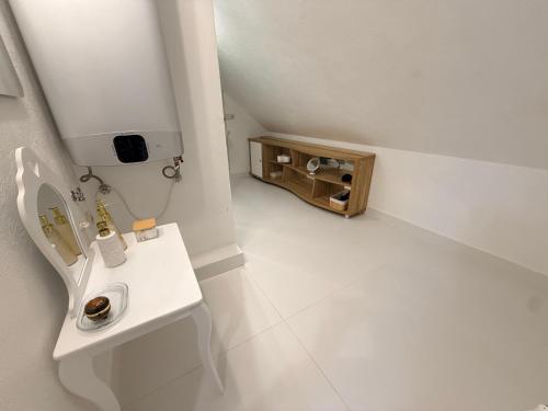 a white bathroom with a sink and a table at Rose & Vintage Mansard in Kuldīga