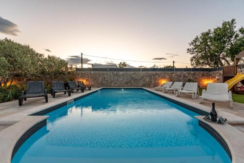 a swimming pool with chairs and a slide at Villa Elder ZadarVillas in Donji Lepuri