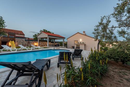 a swimming pool with chairs and a house at Villa Elder ZadarVillas in Donji Lepuri