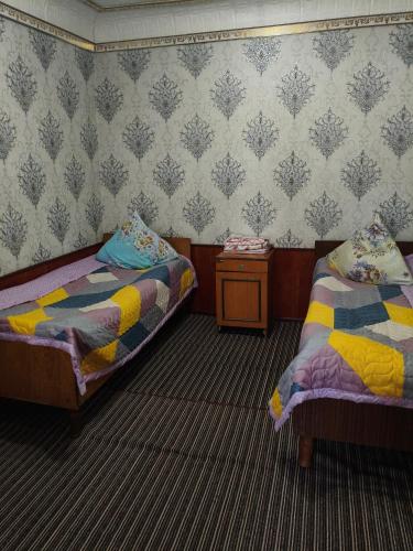a room with two beds and a side table at Geust house Paradise in Arslanbob