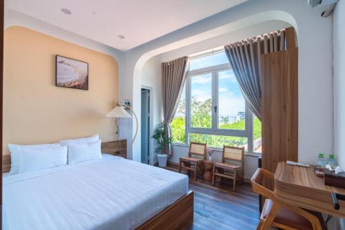 a bedroom with a bed and a desk and a window at May Bliss Villa in Danang