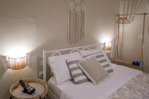 ein Schlafzimmer mit einem weißen Bett, Kissen und einem Tisch in der Unterkunft Aerides Studios in Methana