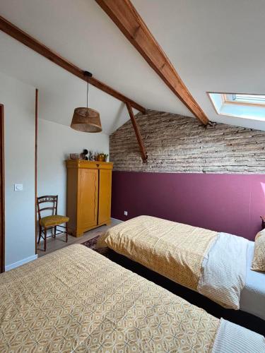 a bedroom with two beds and a brick wall at Gîte La Vielle Forge in Virazeil