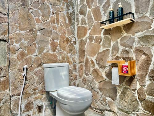 a bathroom with a toilet and a stone wall at Omah Osing Ijen Banyuwangi in Licin