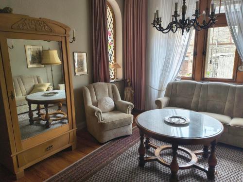 a living room with a chair and a table and a mirror at Bed & Breakfast - Haus Hubertus in Brauneberg