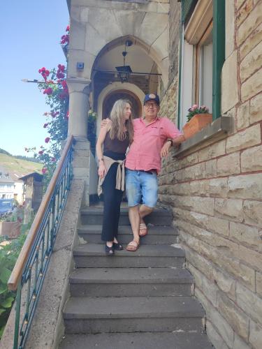 a man and a woman standing on the stairs of a building at Bed & Breakfast - Haus Hubertus in Brauneberg