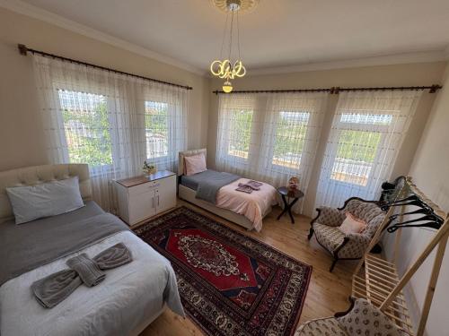 a bedroom with two beds and a chair and windows at Kapadokya Denizhan Villa in Ürgüp