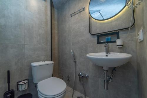 a bathroom with a toilet and a sink and a mirror at Hotel Voyager in Tbilisi City