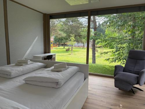 a bedroom with a white bed and two chairs at Zbilje Lakeside Apartment in Medvode