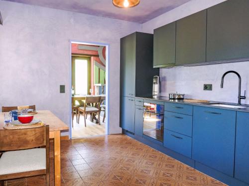 a kitchen with blue cabinets and a table and a dining room at Apartment Casa Malva by Interhome in Malvaglia