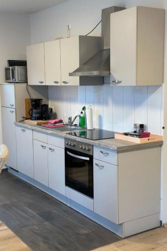 a kitchen with white cabinets and a stove top oven at Apartment FEWO „Am Stausee“ by Interhome in Friesoythe