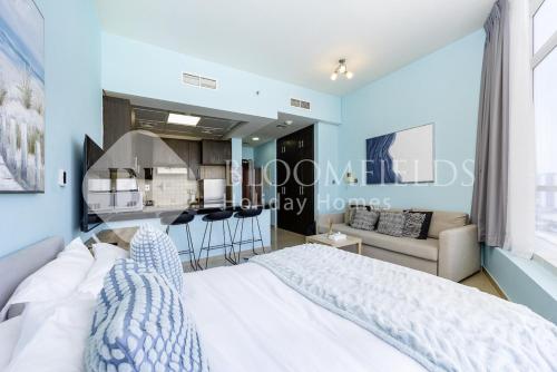 a bedroom with a white bed and a kitchen at Bloomfields Studio in Hydra Avenue - Reem in Abu Dhabi