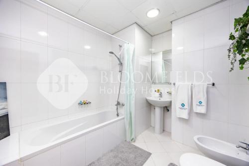 a white bathroom with a tub and a sink at Bloomfields Studio in Hydra Avenue - Reem in Abu Dhabi