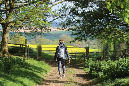 a woman walking down a dirt path with a fence at Cotswold Townhouse - Adults Only in Stow on the Wold