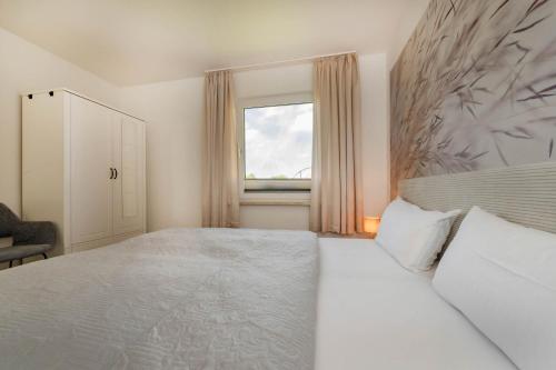 a bedroom with a large white bed and a window at Ferienhaus Seebrise in Loddin