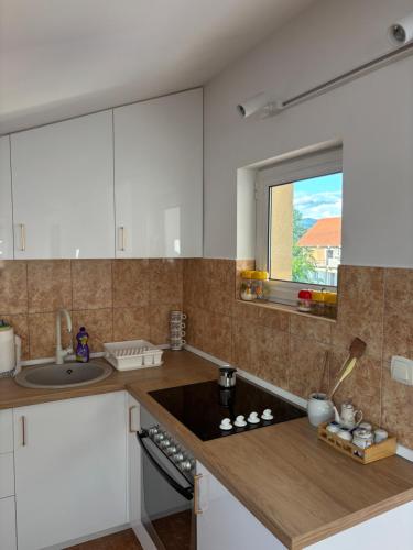 a kitchen with white cabinets and a sink and a window at Family rest apartments in Nikšić