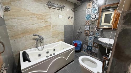 a bathroom with a tub and a sink and a toilet at Countryside Himalayan Resort in Manāli