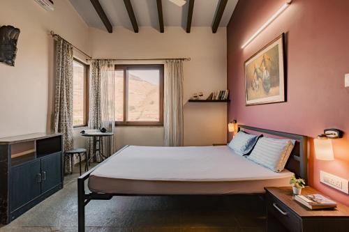 a bedroom with a bed and a desk and a window at Nivaant Villa by StayAtlas in Igatpuri
