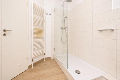 a white bathroom with a shower and a tub at Ferienhaus Alisch Fewo 2 in Warnemünde
