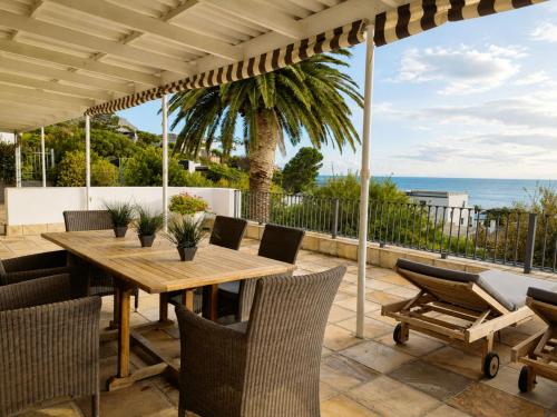 an outdoor patio with a wooden table and chairs at Amazing View Villa, Sleeps 9 in Gordonʼs Bay