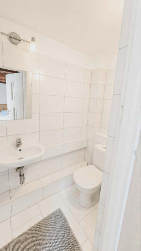 a white bathroom with a toilet and a sink at Pokoje Gościnne w Spichlerzu in Ustka