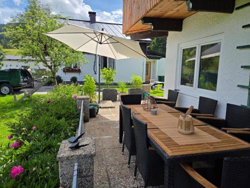 a wooden table with chairs and an umbrella on a patio at Ferienhaus DaPfusterer in Bad Mitterndorf